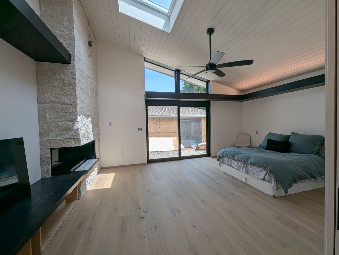 Primary bedroom with stone wall and ceiling fan