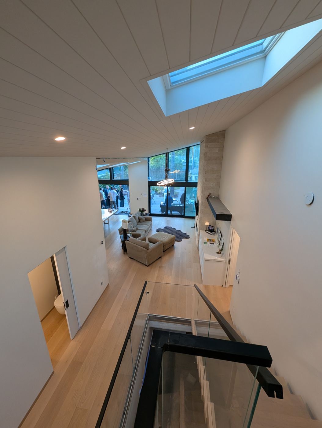 Floating oak stair with glass rail beneath a skylight